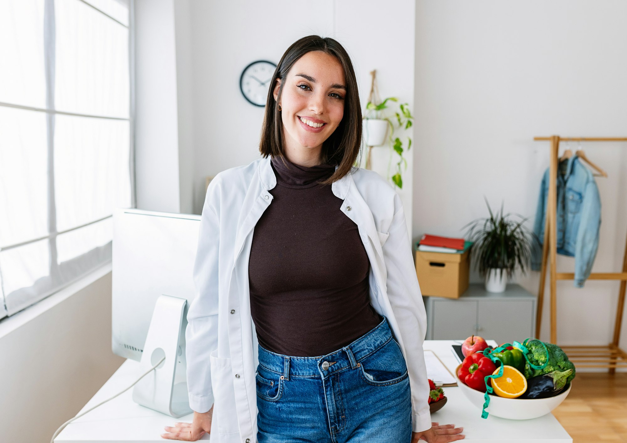 Smiling portrait of young female nutritionist doctor standing at desk office